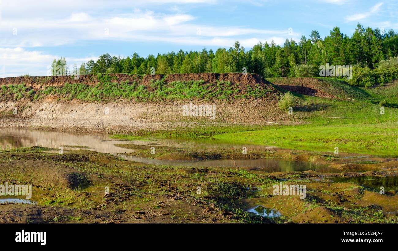 Piccoli canali e acqua del fiume su una ripida collina con una foresta nell'estremo nord nella taiga di Yakutia. Foto Stock