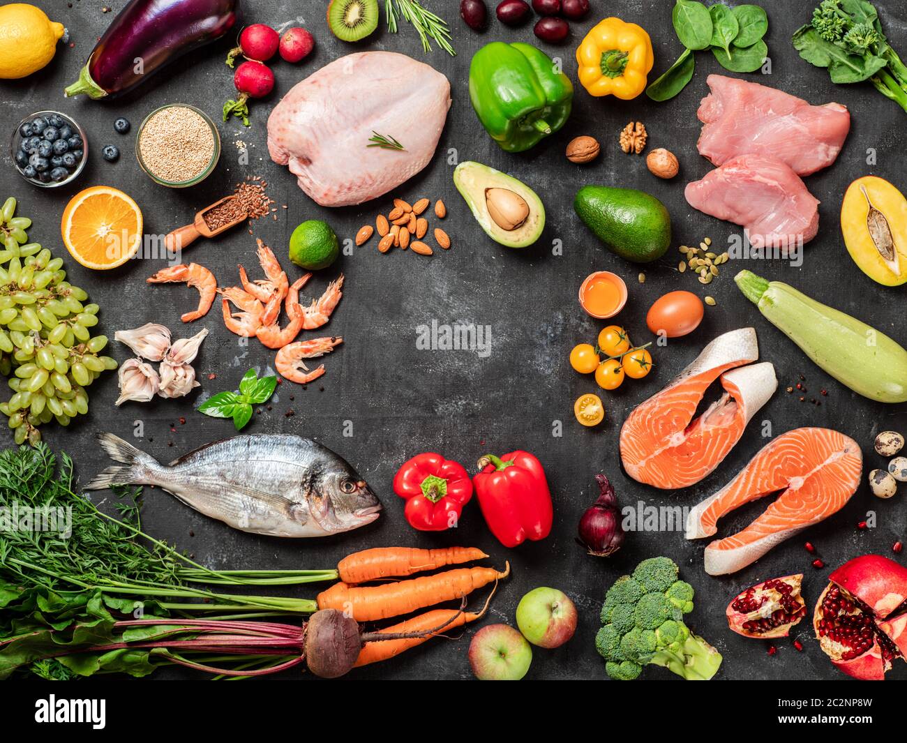Pegan dieta conept con spazio di copia al centro. Vegan più paleo dieta ingredienti alimentari - verdure, frutta, carne cruda e pesce su sfondo scuro. Vi Foto Stock