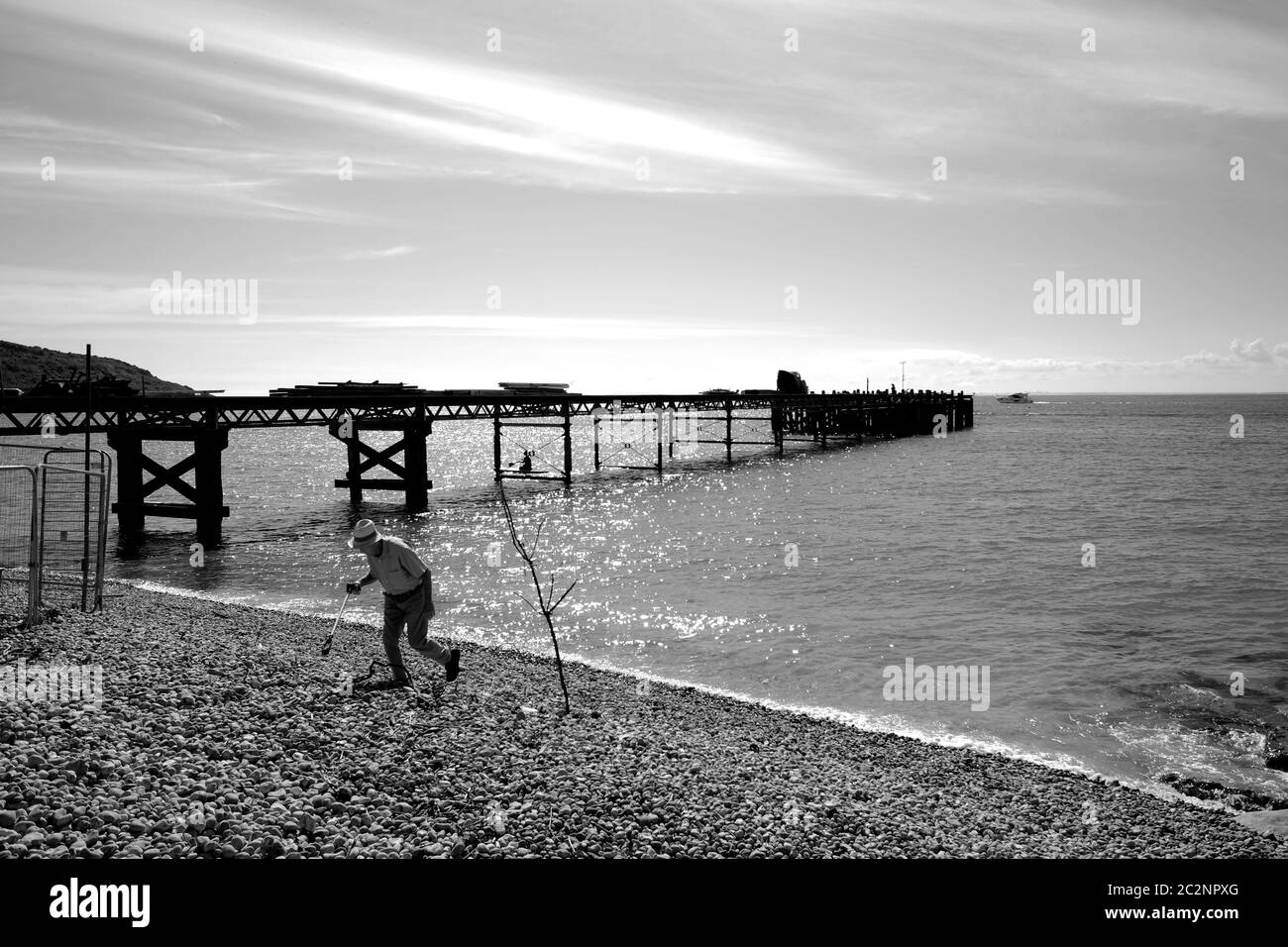 Ritirata OAP Old Age pensionata raccolta rifiuti su Totland Bay spiaggia in estate durante il tempo soleggiato e luminoso sul mare Foto Stock