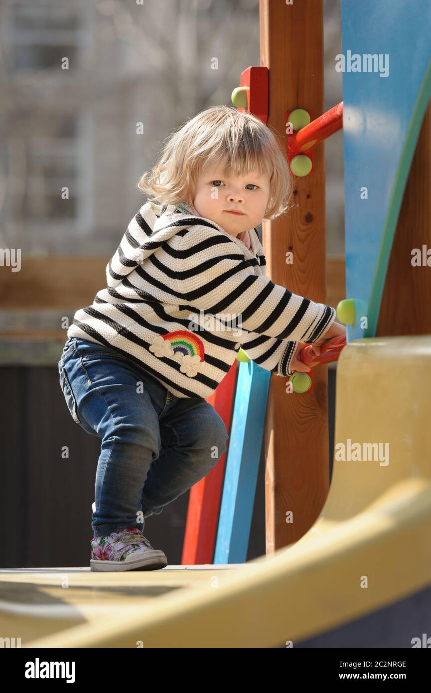 carina bambina quasi scivolando giù lo scivolo dei bambini Foto Stock
