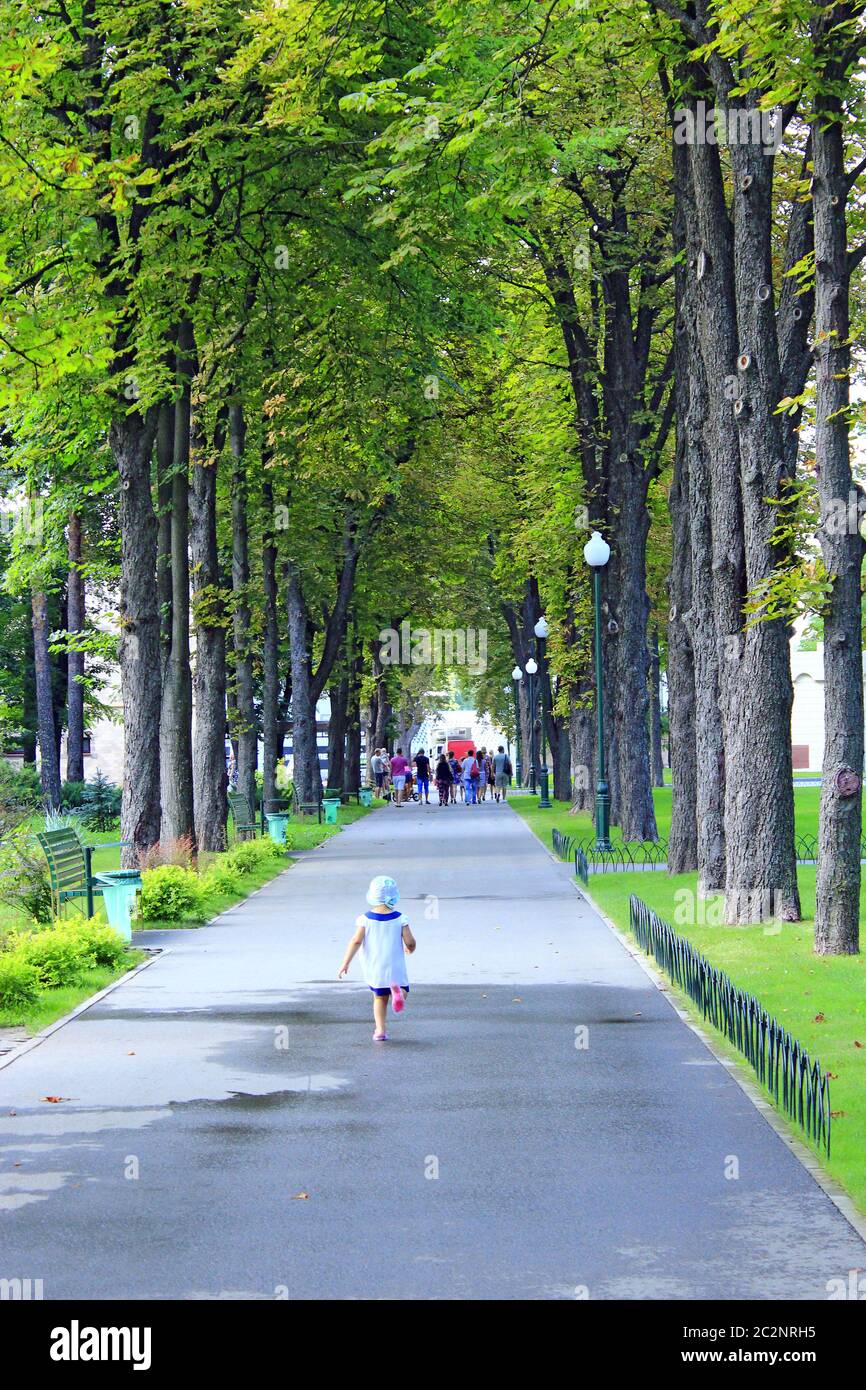Bambina che corre nel parco cittadino. Baby walking da solo in bellissimo parco estivo Foto Stock