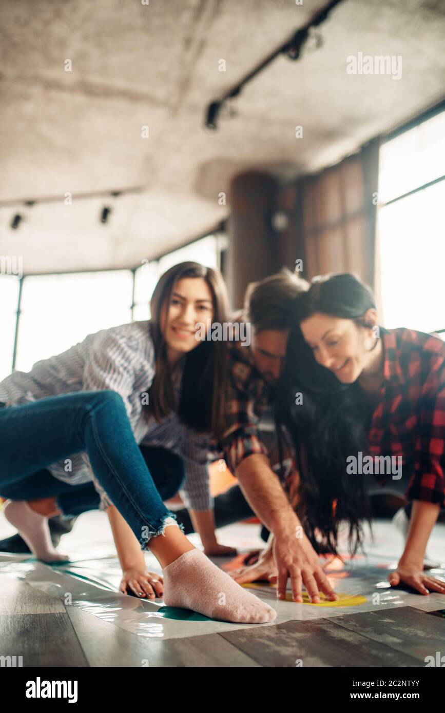 Gruppo di studenti giocando twister gioco. La gioventù in funny pone sul pavimento, intrattenimento per azienda attiva Foto Stock