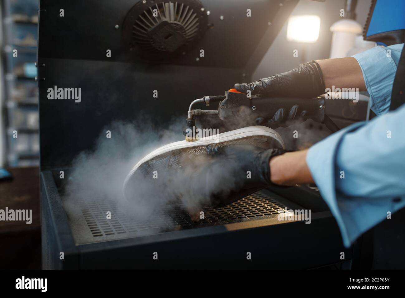 Calzaturiero lavora le scarpe su macchine speciali, servizio di riparazione calzature. Abilità artigiana, laboratorio di calzatureria, lavori padronali con stivali Foto Stock