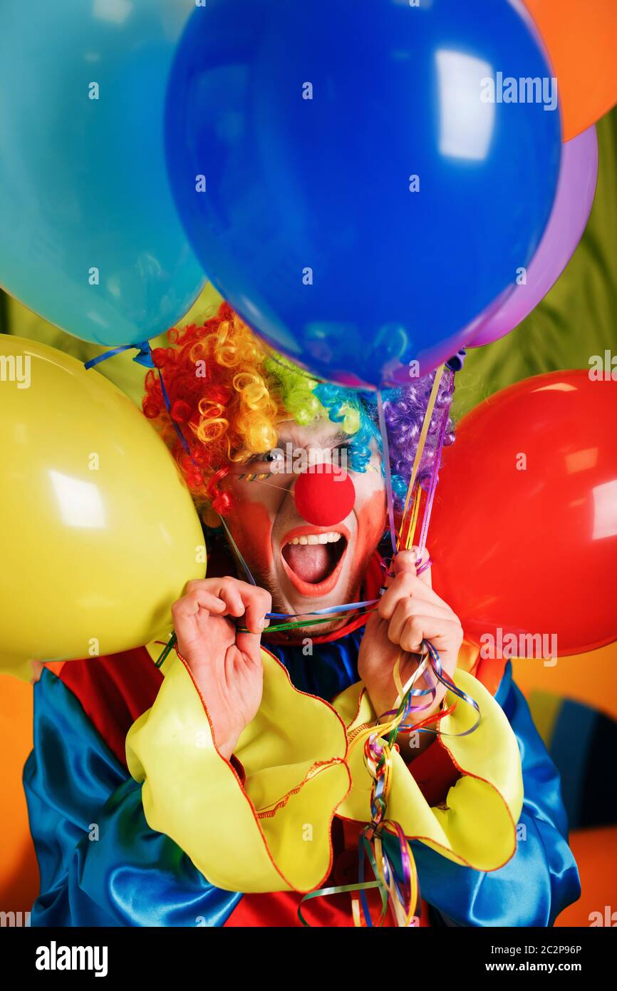 Clown sorridente con un mazzo di palloncini colorati. Concetto di circo umoristico. Foto Stock