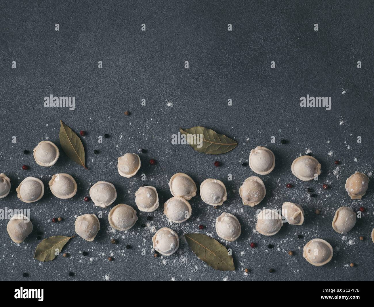 Bella pelmeni crudi sparsi su sfondo di marmo Foto Stock