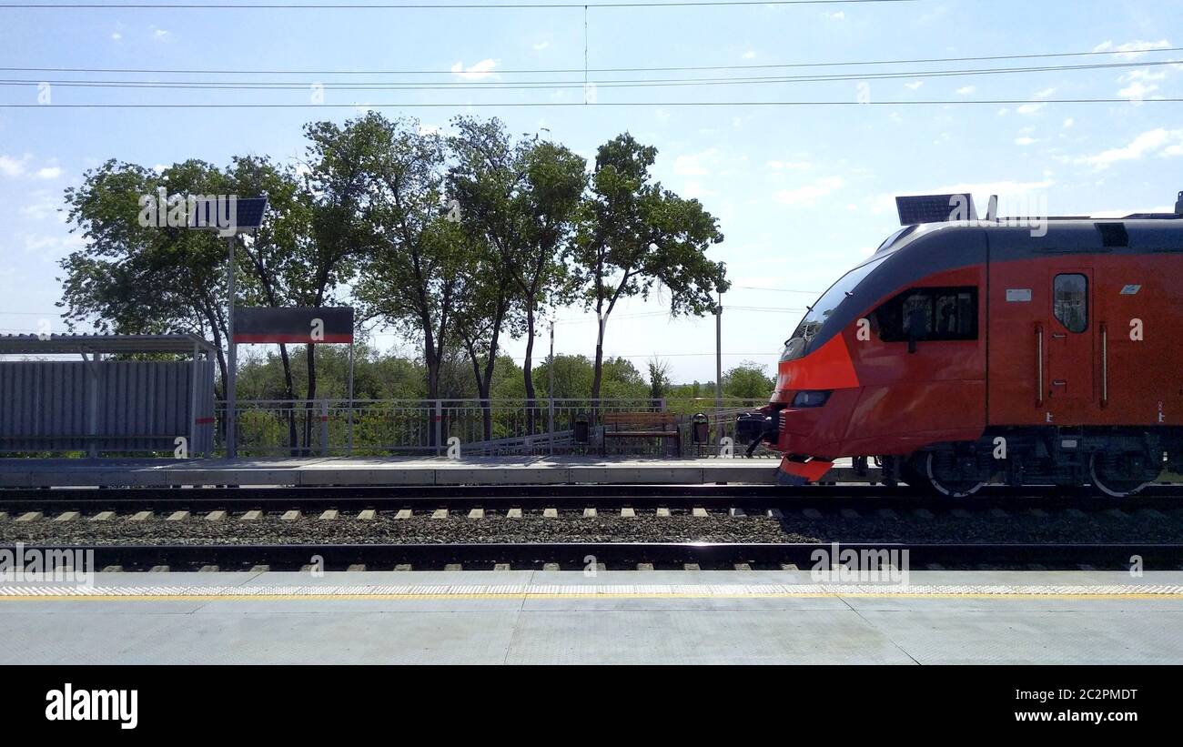 Il treno rosso arriva alla stazione, vista frontale laterale. Foto Stock