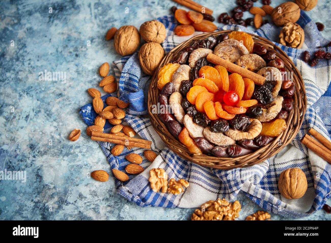 Composizione di frutta secca e noci in piccolo vaso in vimini collocato sul tavolo di pietra Foto Stock
