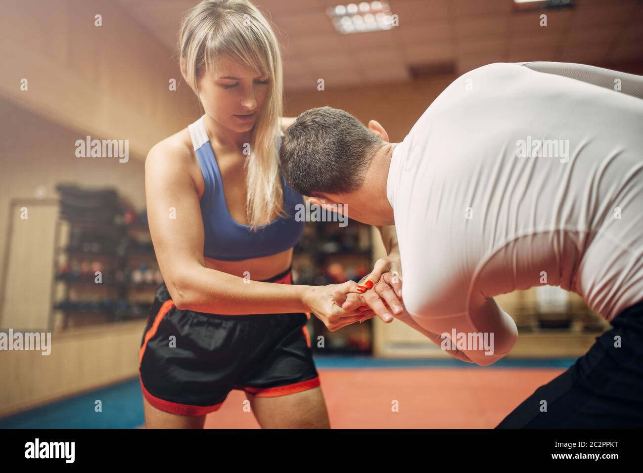 Persona di sesso femminile rende doloroso presa della mano, auto-difesa allenamento con connettore maschio di tipo personal trainer, palestra interno su sfondo. Donna sulla difesa di auto in treno Foto Stock