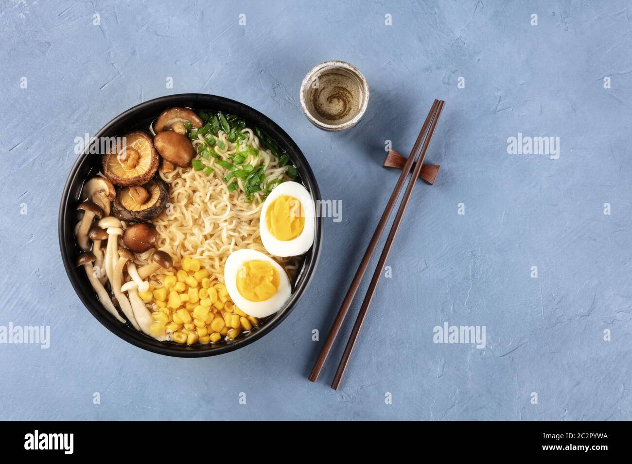 Ramen. Tagliatelle di Soba con uova sode, funghi shiitake e verdure, sparate dalla cima con bastoncini, sake, e un posto f Foto Stock