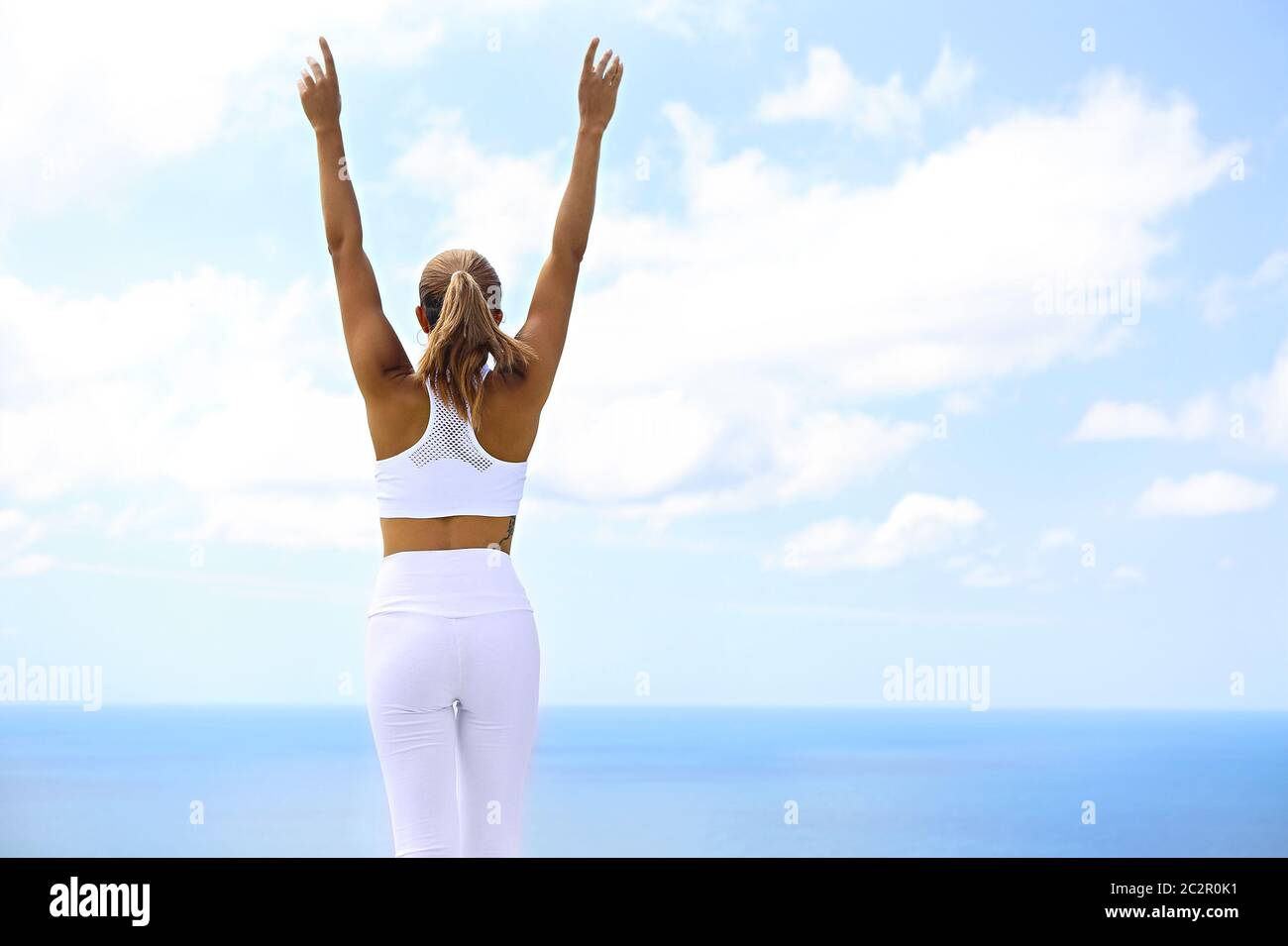 Bella donna che fa esercizi di stretching in spiaggia Foto Stock