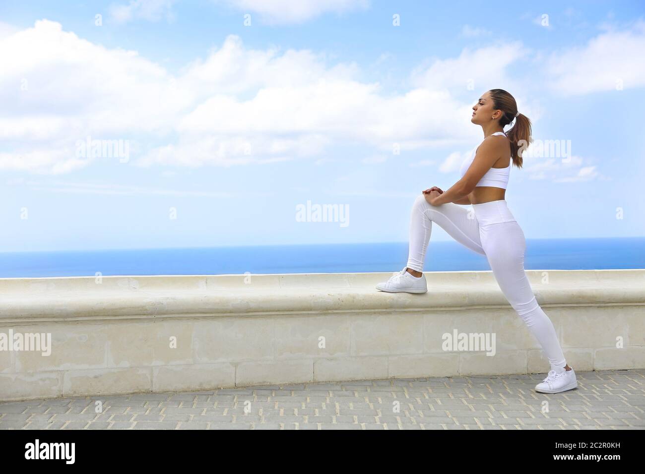 Bella donna che fa esercizi di stretching in spiaggia Foto Stock
