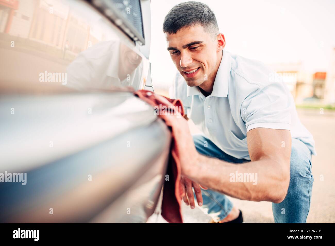 Auto lucidatura esterna sulla stazione di autolavaggio. Uomo di sfregamento del paraurti del veicolo con automobile polacco Foto Stock