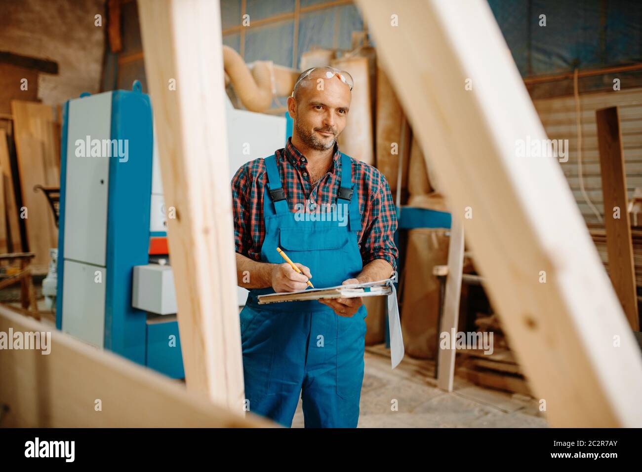 Falegname con taccuino, lavorazione del legno, industria del legname, Falegnameria. Lavorazione del legno in fabbrica di mobili, produzione di prodotti di materiali naturali Foto Stock