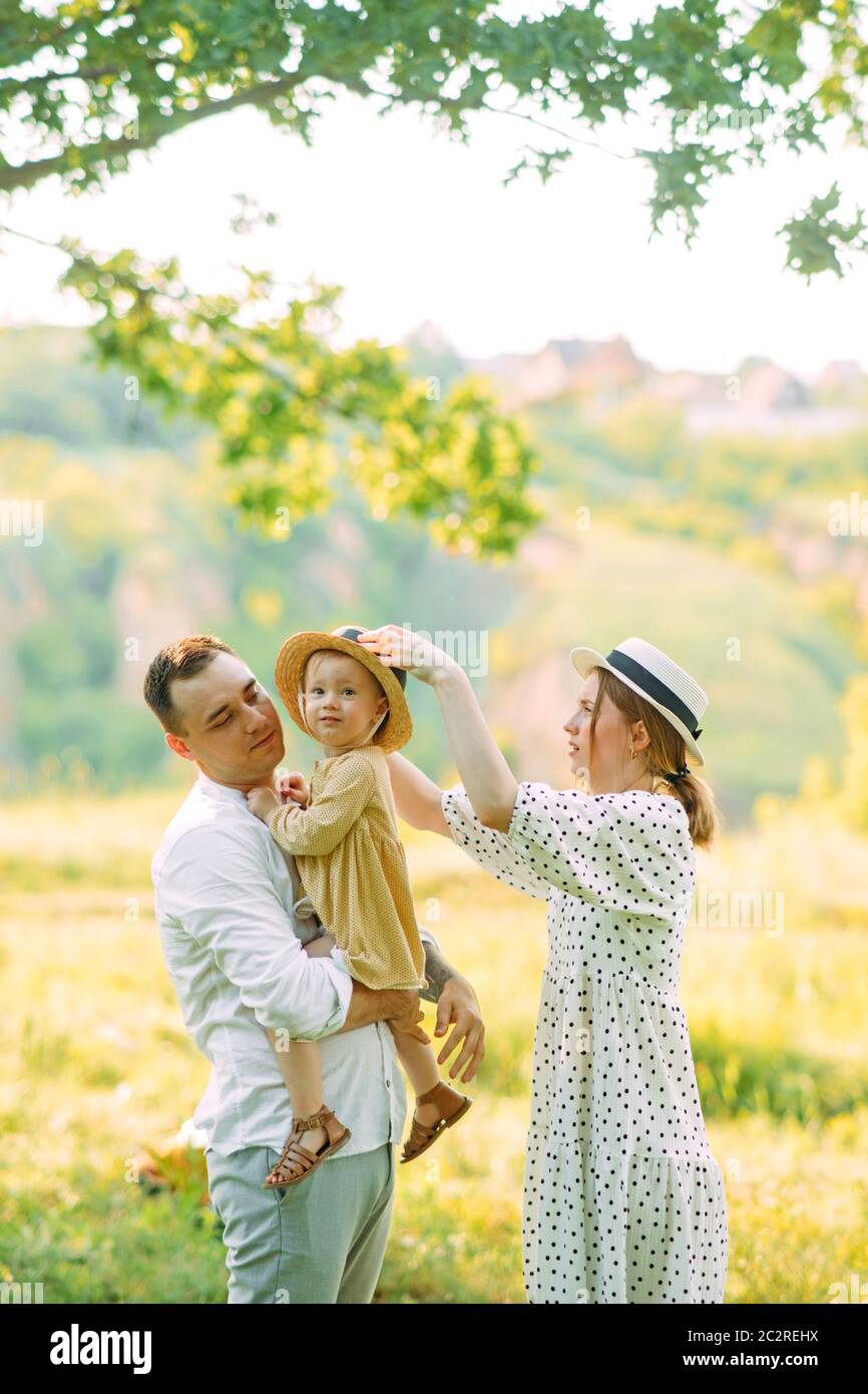 I giovani genitori sono con la loro figlia mentre camminano nel parco. Foto Stock