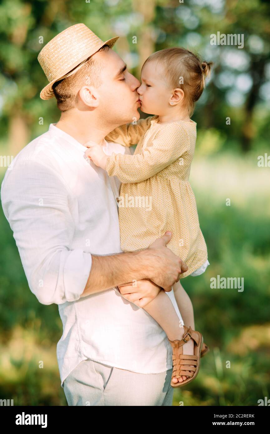 Il giovane padre bacia la figlia mentre cammina nel parco. Foto Stock
