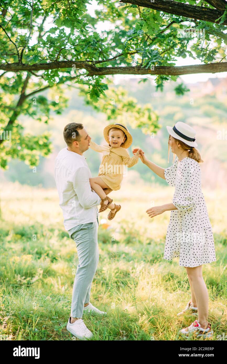 I giovani genitori si divertono e giocano con la figlia mentre camminano nel parco. Foto Stock