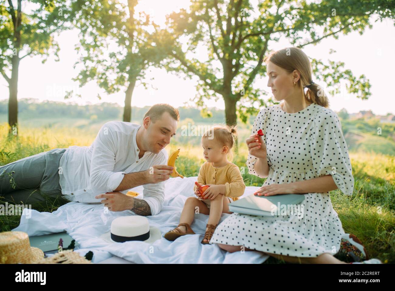 La famiglia con la figlia mangia frutta durante il picnic nel parco. Foto Stock