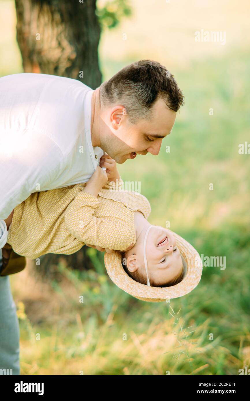 Il giovane padre si diverte e gioca con sua figlia mentre cammina nel parco. Foto Stock