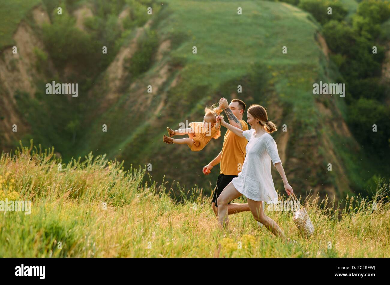 Giovane famiglia con la bambina gioca, ha divertimento, corre e ride allegra. Foto Stock