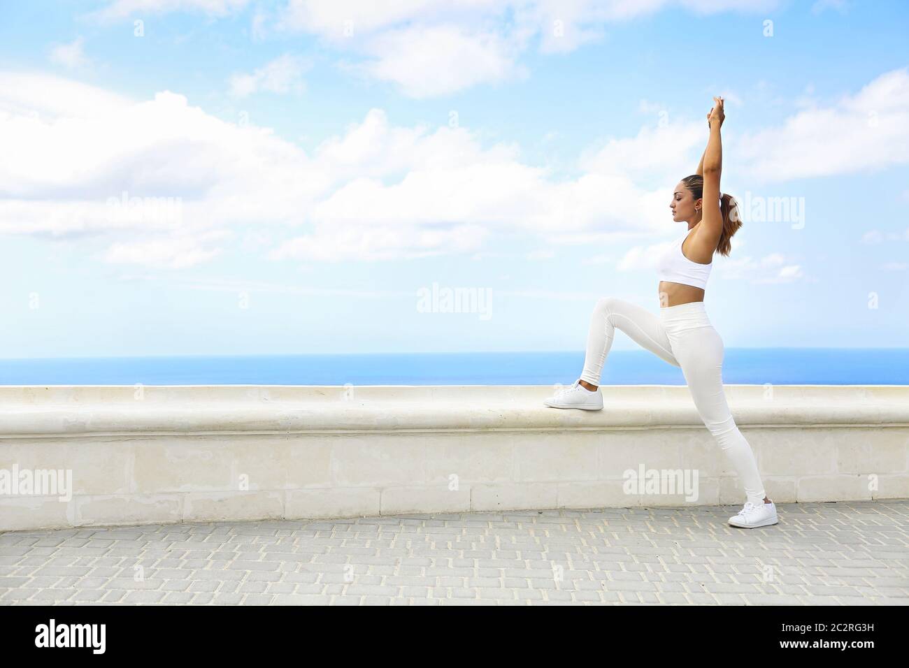 Bella donna che fa esercizi di stretching in spiaggia Foto Stock