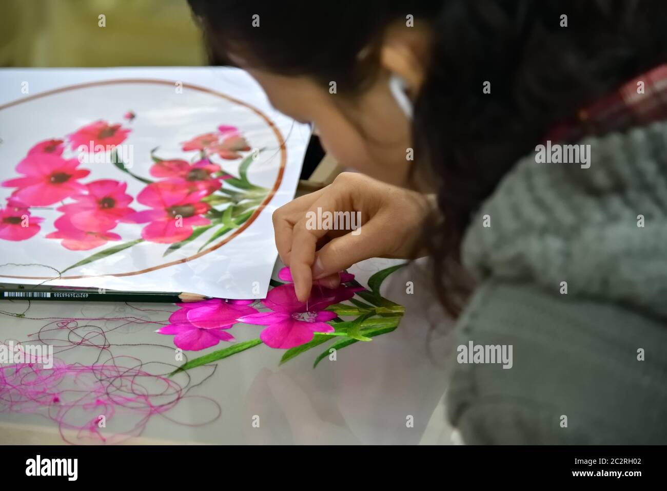 Pyongyang, Corea del Nord - 29 aprile 2019: Operaio di fabbrica di donna con ago e filo di seta su tela. Focus sul neddle Foto Stock