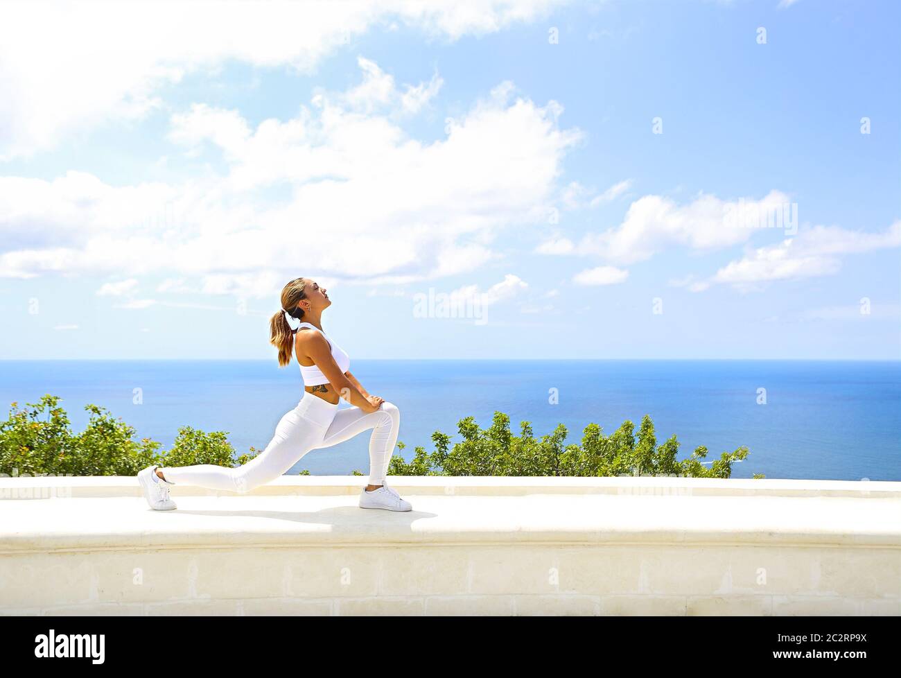Bella donna che fa esercizi di stretching in spiaggia Foto Stock