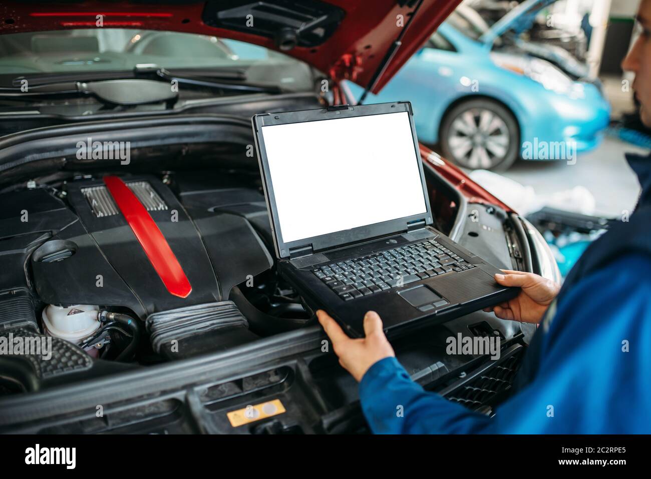 Ingegnere con laptop computer rende la diagnostica del motore per auto in auto-servizio. Cablaggio del veicolo ispezione Foto Stock