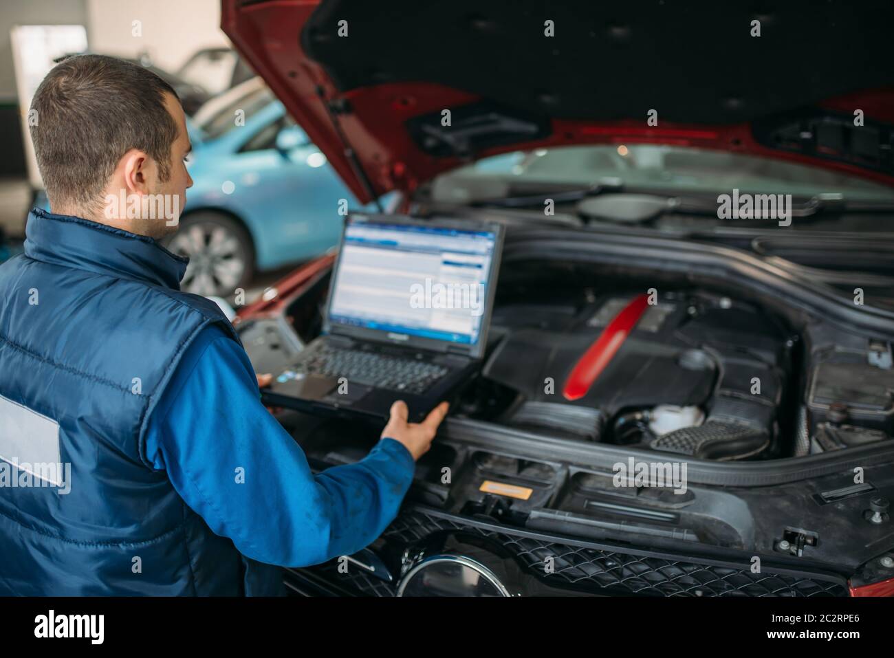 Ingegnere con laptop computer rende la diagnostica del motore per auto in auto-servizio. Cablaggio del veicolo ispezione Foto Stock