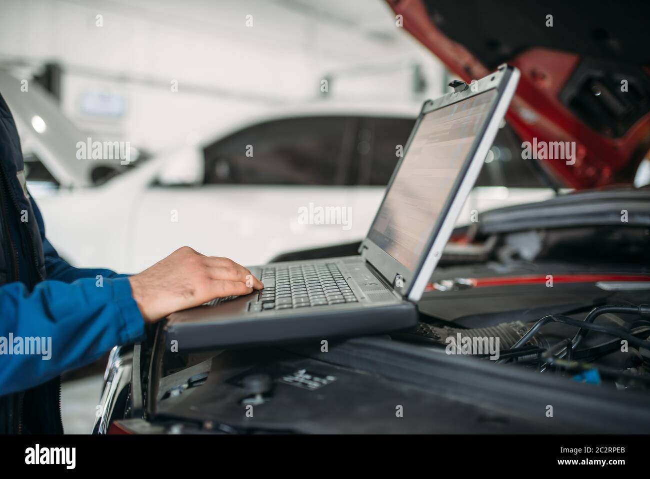 Ingegnere calcolatore rende la diagnostica della vettura in auto service. Cablaggio del veicolo ispezione Foto Stock