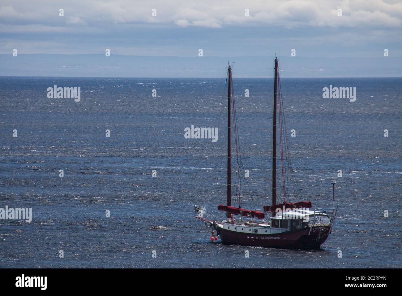 Una barca a vela che riposa nelle acque del fiume Saint Laurent di fronte all'Hotel Tadoussac nella piccola città di Tadoussac, Quebec, Canada Foto Stock