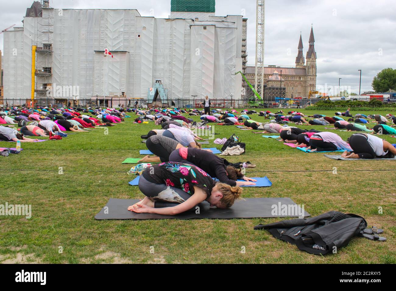 Un grande gruppo di persone sta facendo una lezione di yoga in un prato urbano a Ottawa, Ontario, Canada Foto Stock