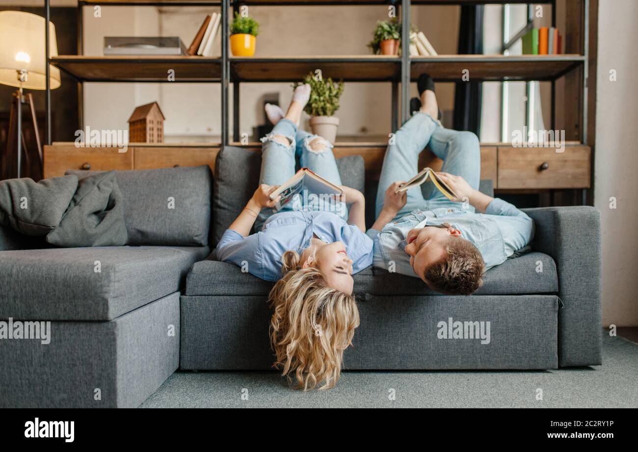 Giovane coppia d'amore con libri sdraiati sul divano capovolto. Marito e  moglie si rilassano nel soggiorno. Buona famiglia che si diverte insieme  Foto stock - Alamy