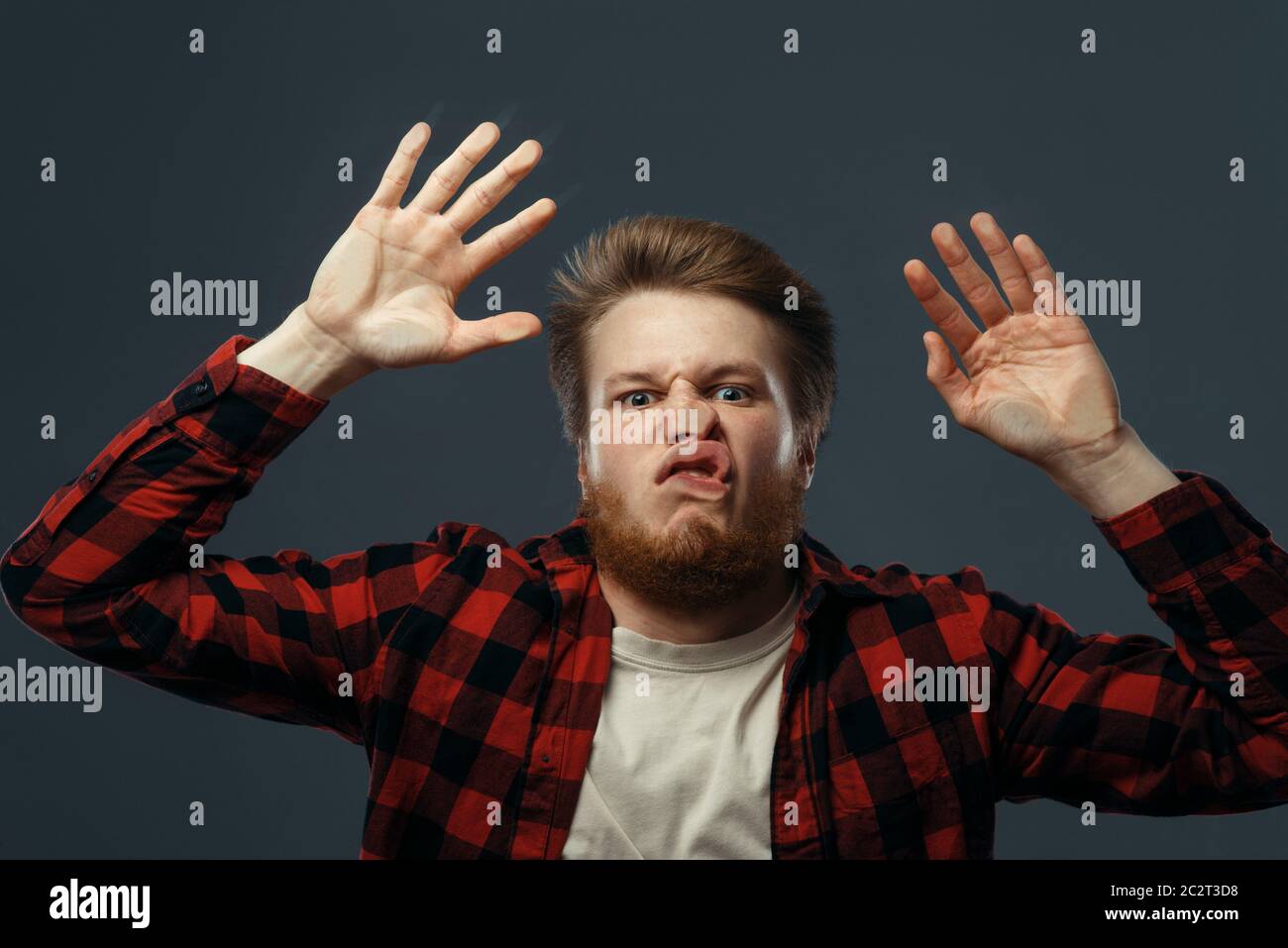 Il volto divertente del giovane schiacciato su vetro trasparente. Uomo con grimace pressato in piedi alla vetrina, umorismo Foto Stock