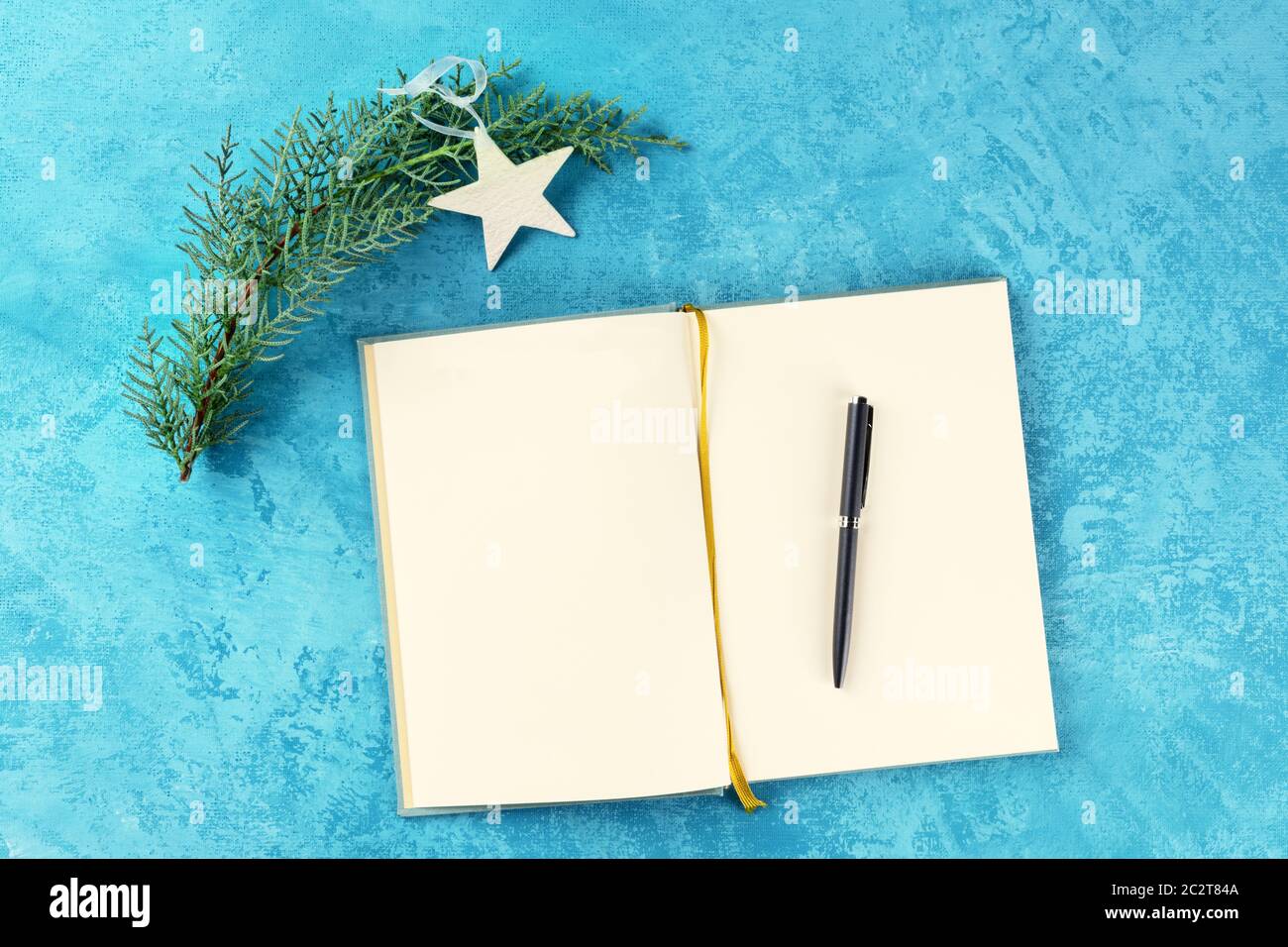 Le risoluzioni di nuovo anno o concetto di lista di bucket, un piatto punto superiore di un giornale su uno sfondo turchese con una penna, una Christma Foto Stock