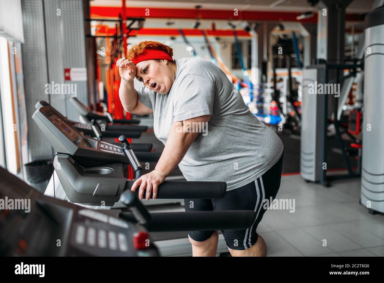 Il sovrappeso stanco donna in esecuzione su un tapis roulant in palestra.  Calorie bruciare, femmina obesi in persona lo sport club Foto stock - Alamy