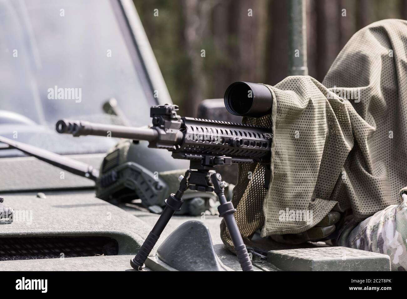 Uomo militare in uniforme camuffata con fucile. Dotato di fucile per la ripresa di cecchini. Uno sniper mascherato mira a un obiettivo. Cecchino con un fucile. Foto Stock