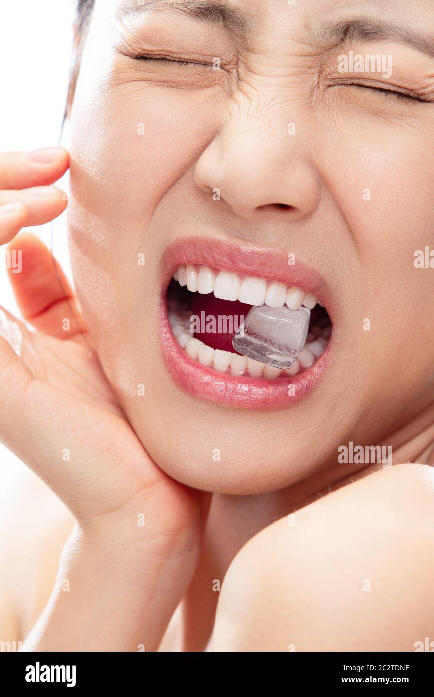 Masticare il ghiaccio improvvisamente dentifricio giovane donna Foto Stock