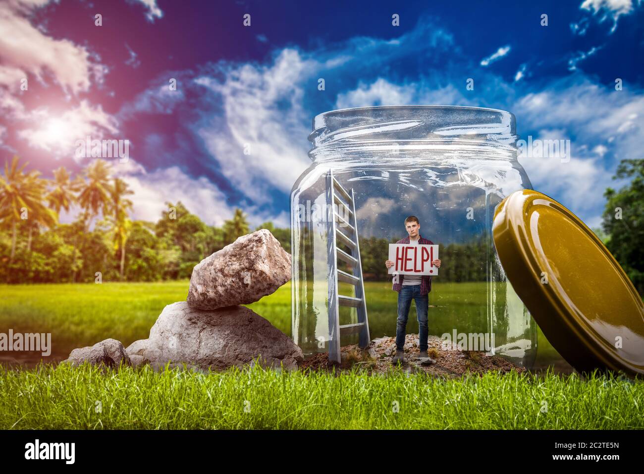 La paura della solitudine concetto, giovane uomo impotente con segno guida in piedi in un grande vaso di vetro sul prato verde. La depressione delle persone sole Foto Stock