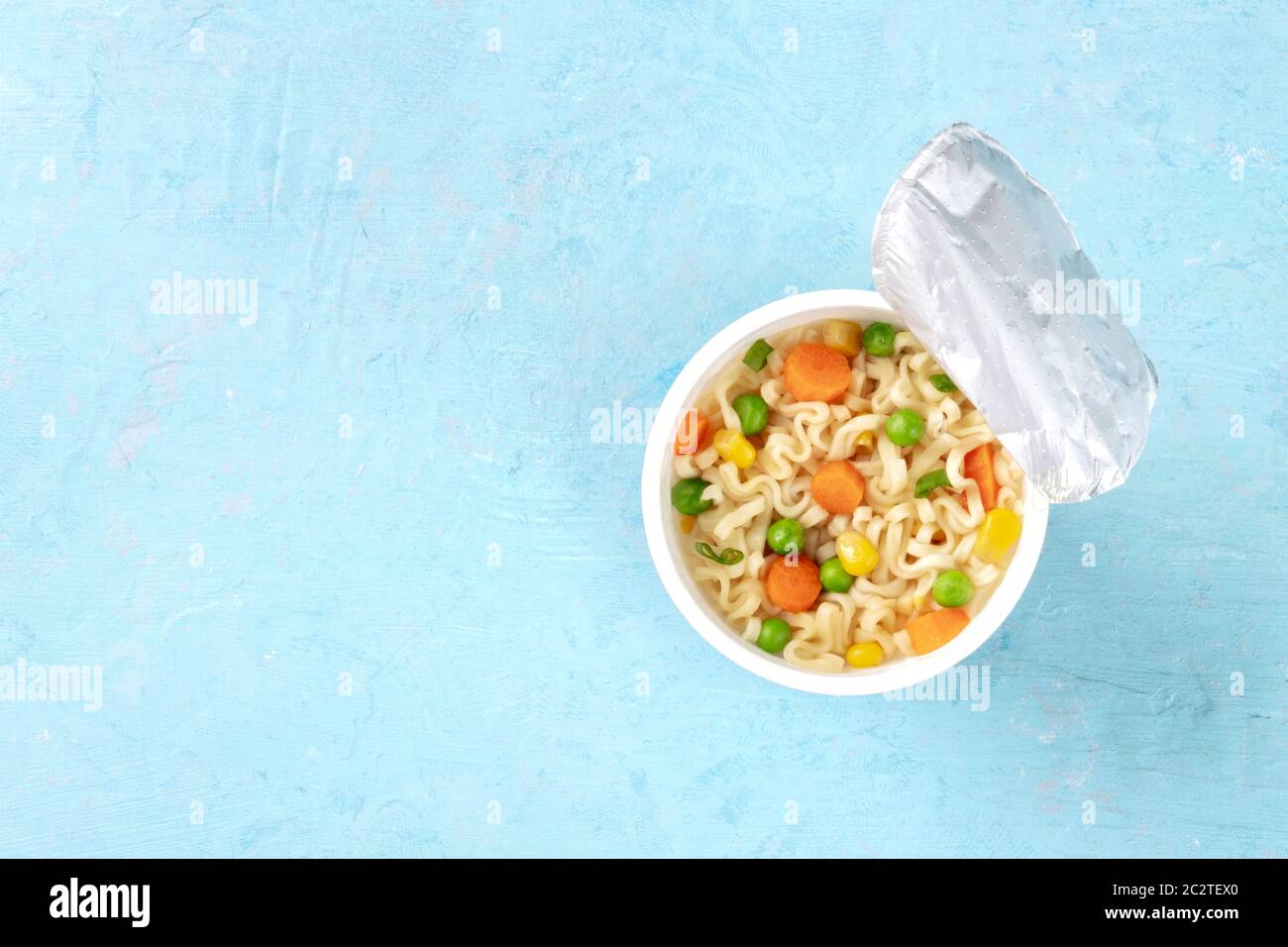 Ramen cup, tagliatelle istante in una tazza di plastica, overhead shot su uno sfondo blu con un posto per il testo Foto Stock