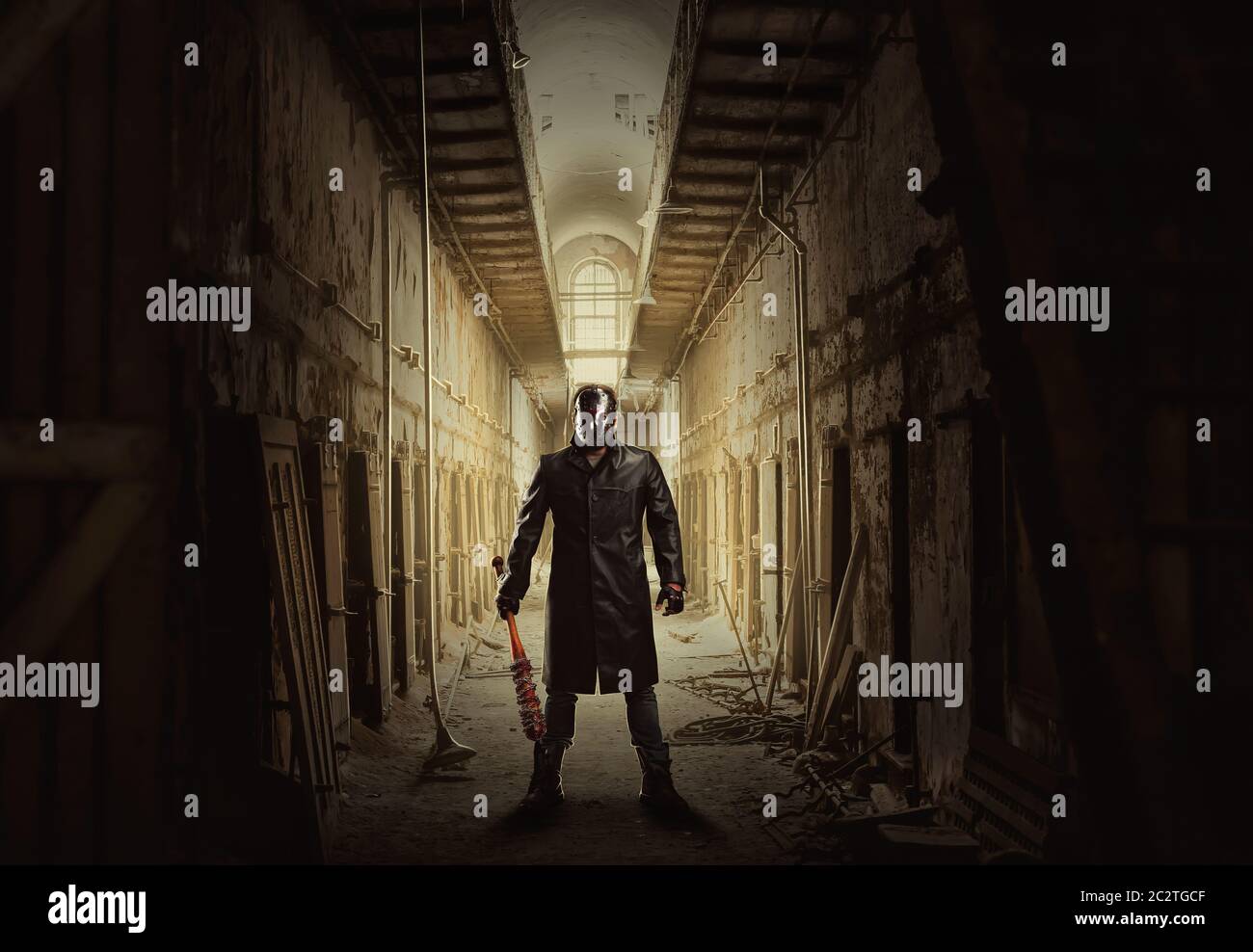 Serial killer con pipistrello sanguinoso in mano in piedi nel mezzo di un corridoio di grunge abbandonato edificio. Foto Stock