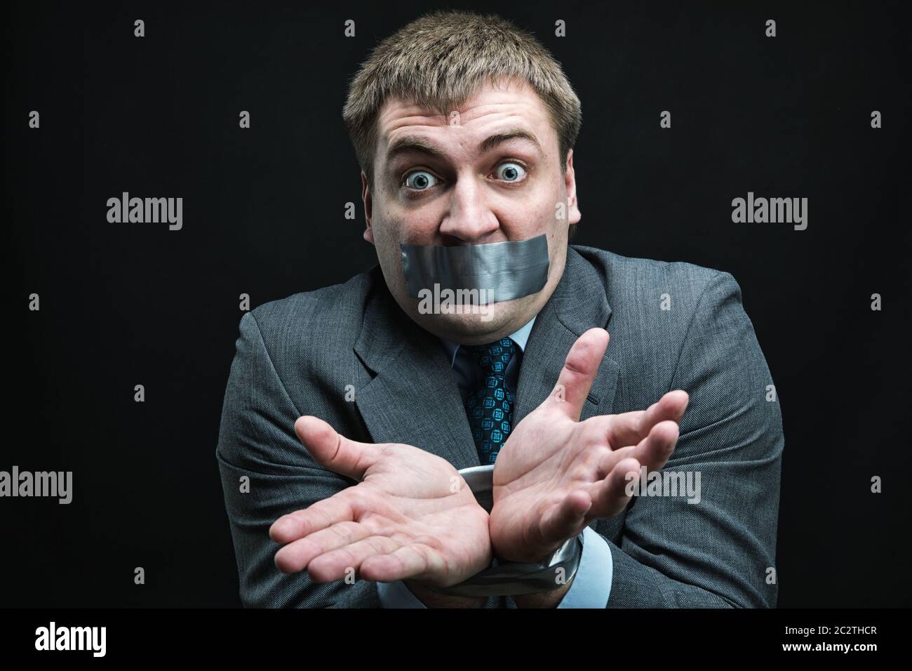 Imprenditore con bocca e mani coperte da nastro adesivo impedendo discorso, studio shoot Foto Stock