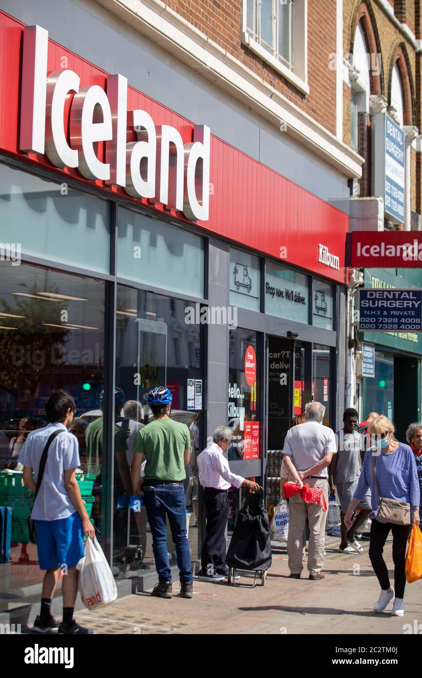 I clienti si accodano per il supermercato Islanda a Kilburn, sulla scia della pandemia di Covid Foto Stock