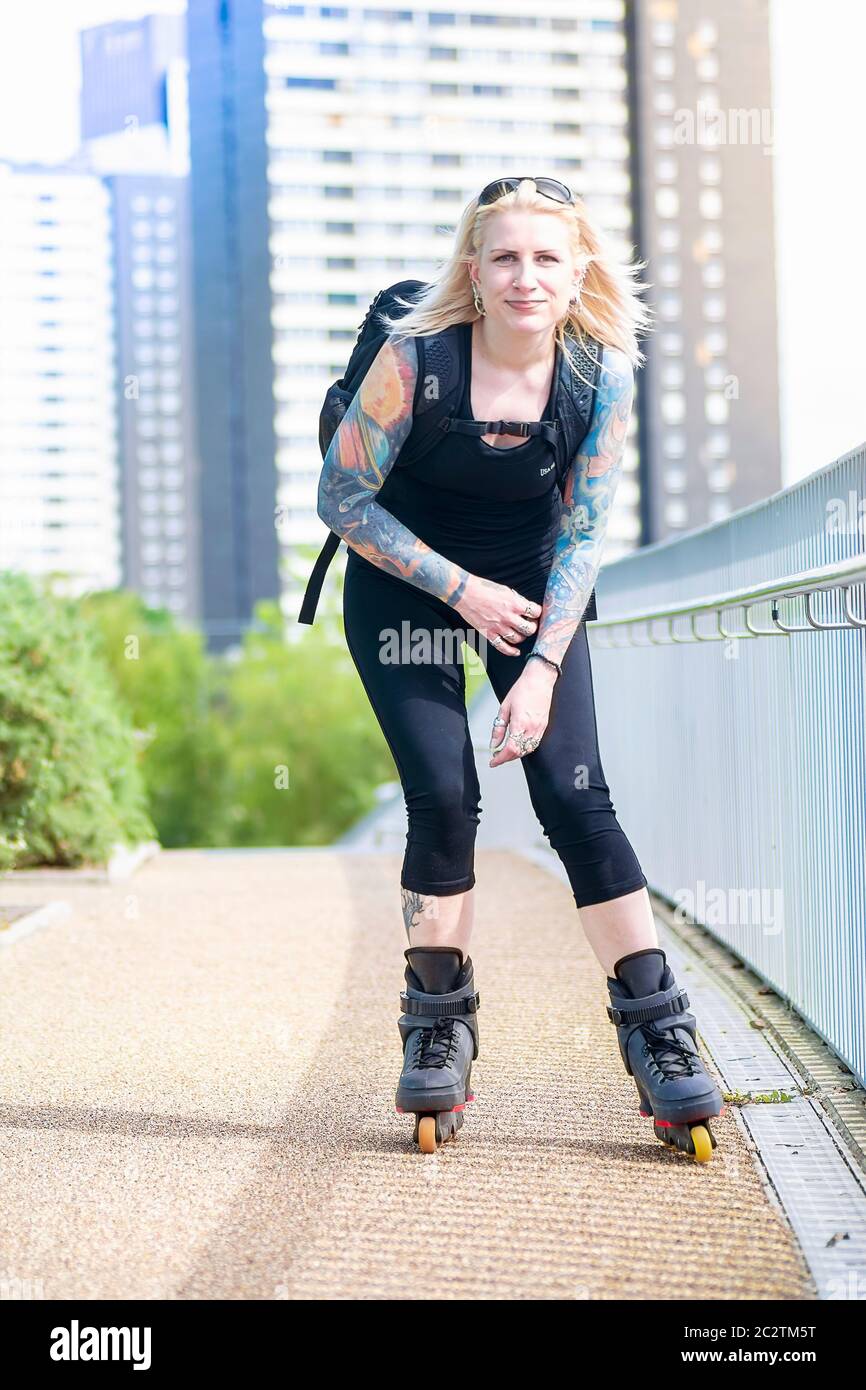 Donna bionda con pattina a rulli tatuaggi Foto Stock