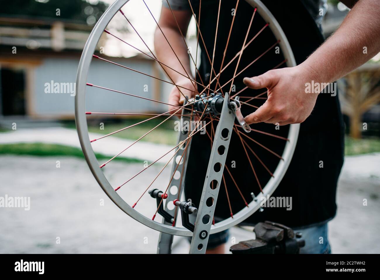 Persona di sesso maschile in grembiule regola bike raggi e ruota con gli  attrezzi di servizio. Workshop di ciclo all'aperto. Ciclismo sport,  professional meccanico di bicicletta Foto stock - Alamy