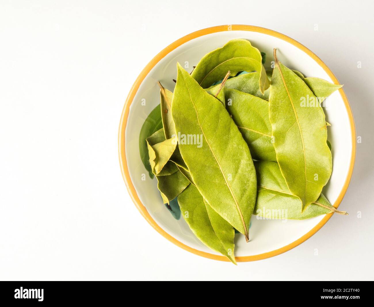 Un piccolo piatto di foglie di alloro essiccato isolato su uno sfondo bianco con spazio di copia Foto Stock