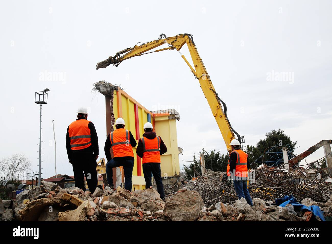Ingegnere mans in casco e giacca che controlla cantiere esterno. Uomo tecnico che guarda i macchinari sul sito di demolizione. Foto Stock