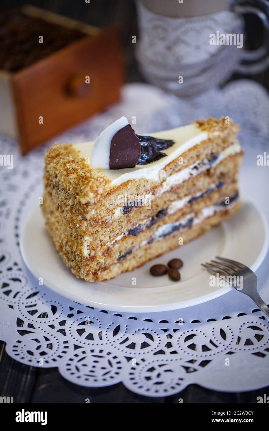Torta con miele e prugne su un piatto bianco. Torta di compleanno. Foto Stock