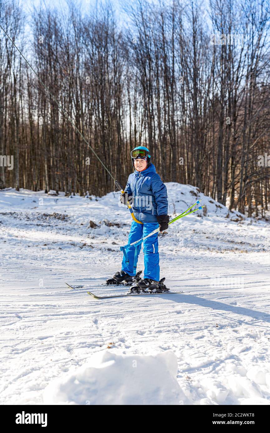 I bambini utilizzano lo skilift Button per raggiungere la cima della zona sciistica di allenamento Foto Stock