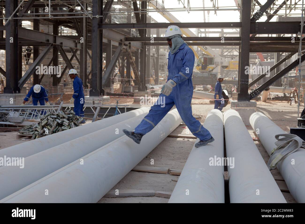 Camminando su tubazioni durante la costruzione di un nuovo impianto petrolifero nel deserto del Sahara. Foto Stock
