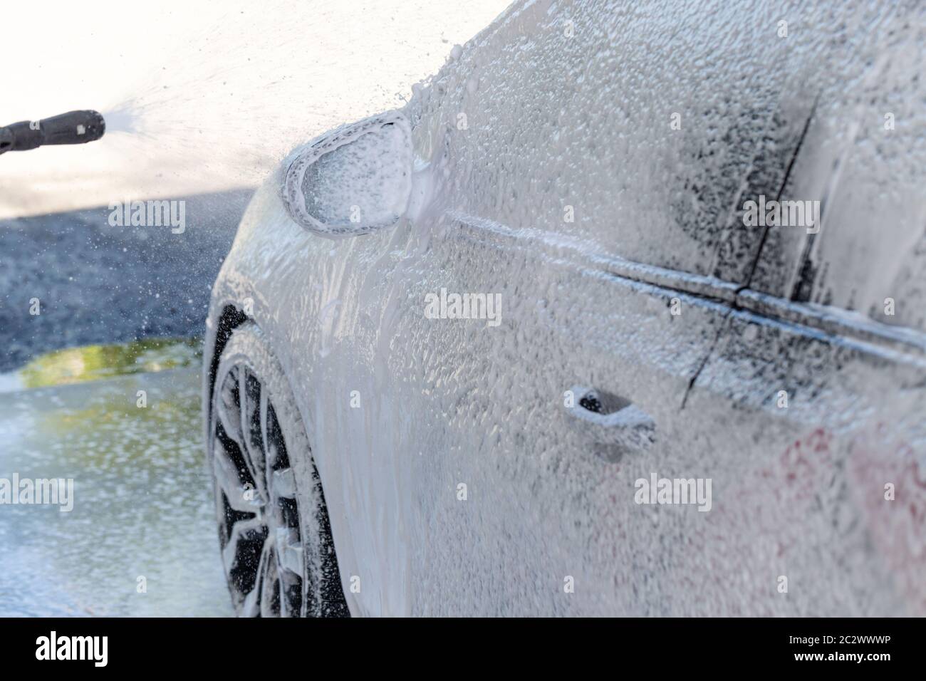 Closeup di lavaggio manuale dell'automobile, pulizia con schiuma, acqua sotto pressione. Autolavaggio self-service con tubo ad alta pressione Foto Stock